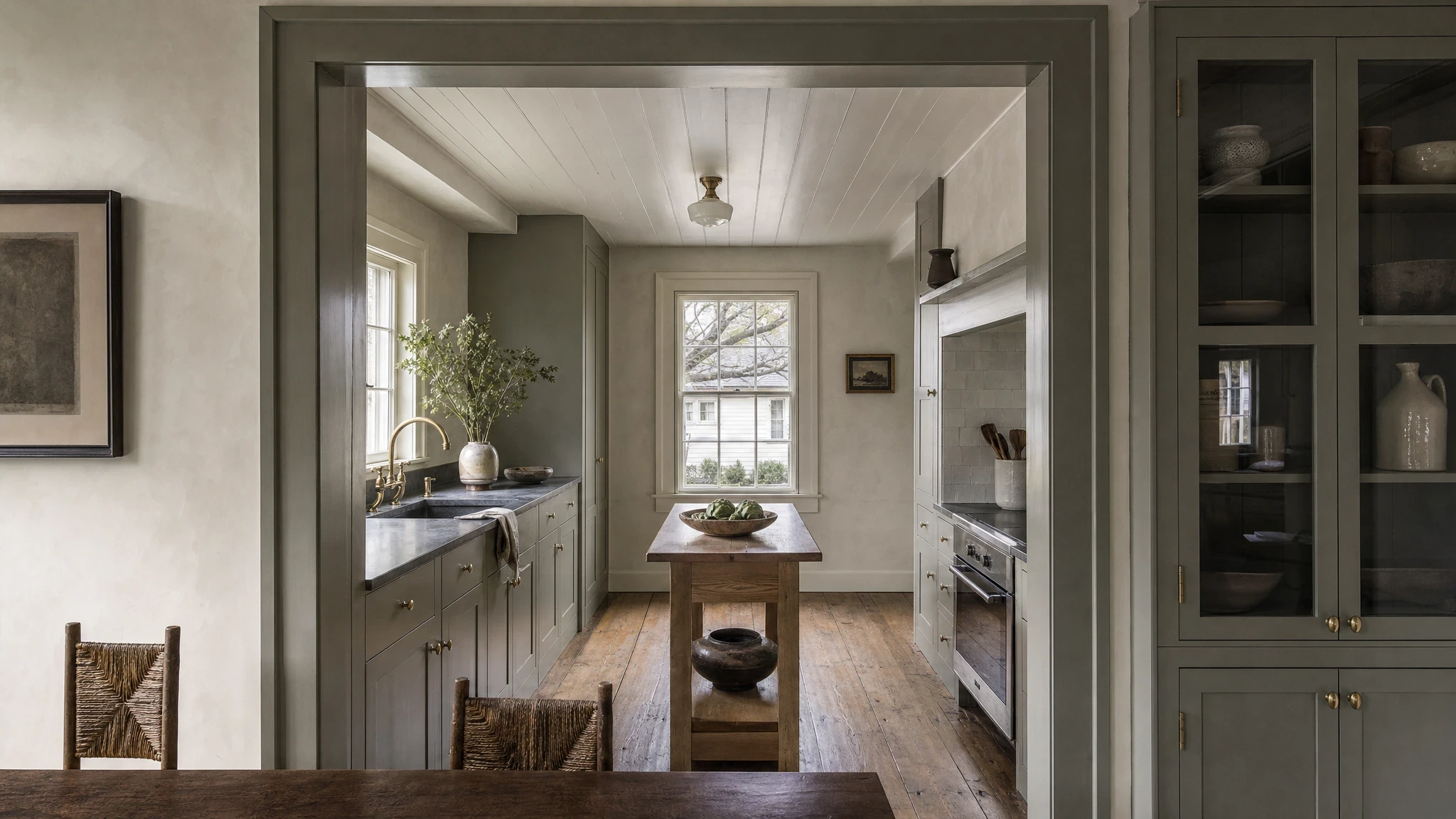 Cape Charles Cottage kitchen study with heart-pine floors, pale tile, kelp-gray cabinetry, and a small white-oak worktable