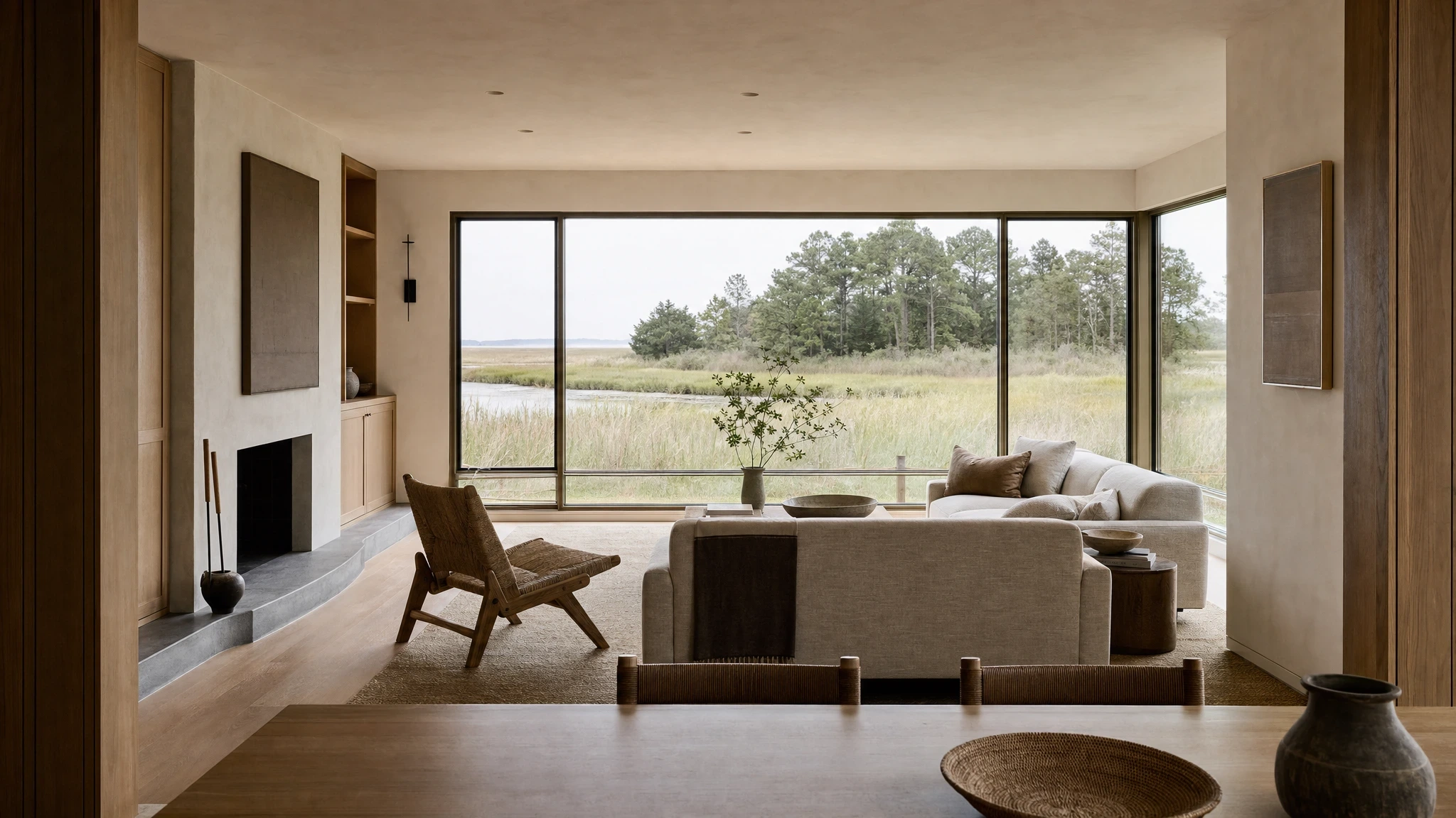Lynnhaven House living study looking toward a low soapstone hearth and a brackish creek through bronze-framed windows